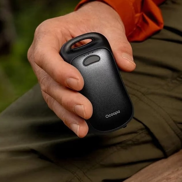 Hand holding black hand warmer with t branding "occopa"