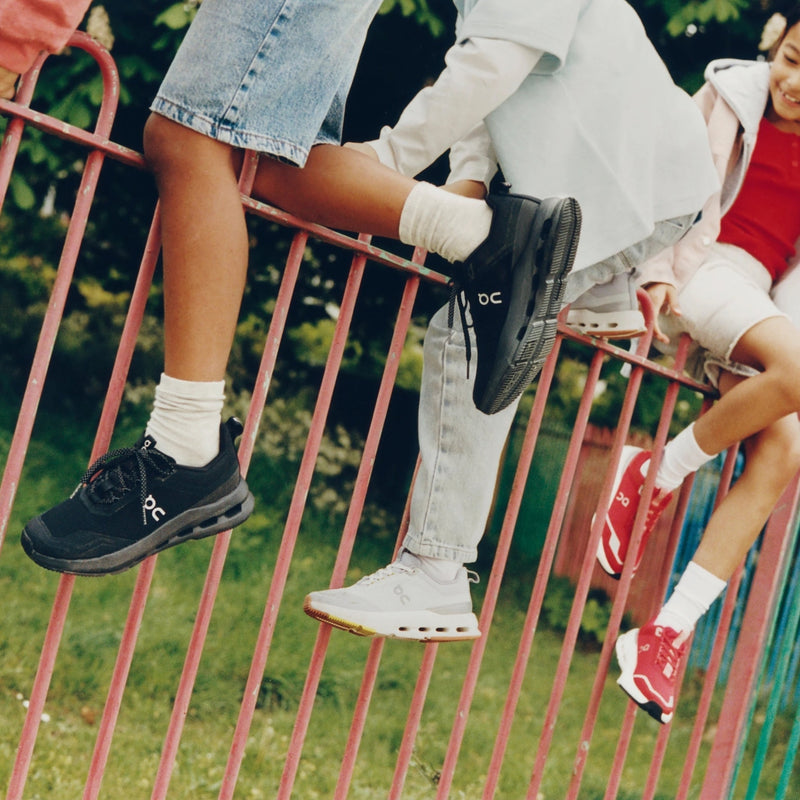 Group of kids climbing over fence with close-up on shoes