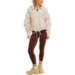 Person wearing a beige jacket, brown leggings, and beige boots on a white background
