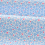 Floral patterned fabric with small blue flowers and pink centers on a light blue background