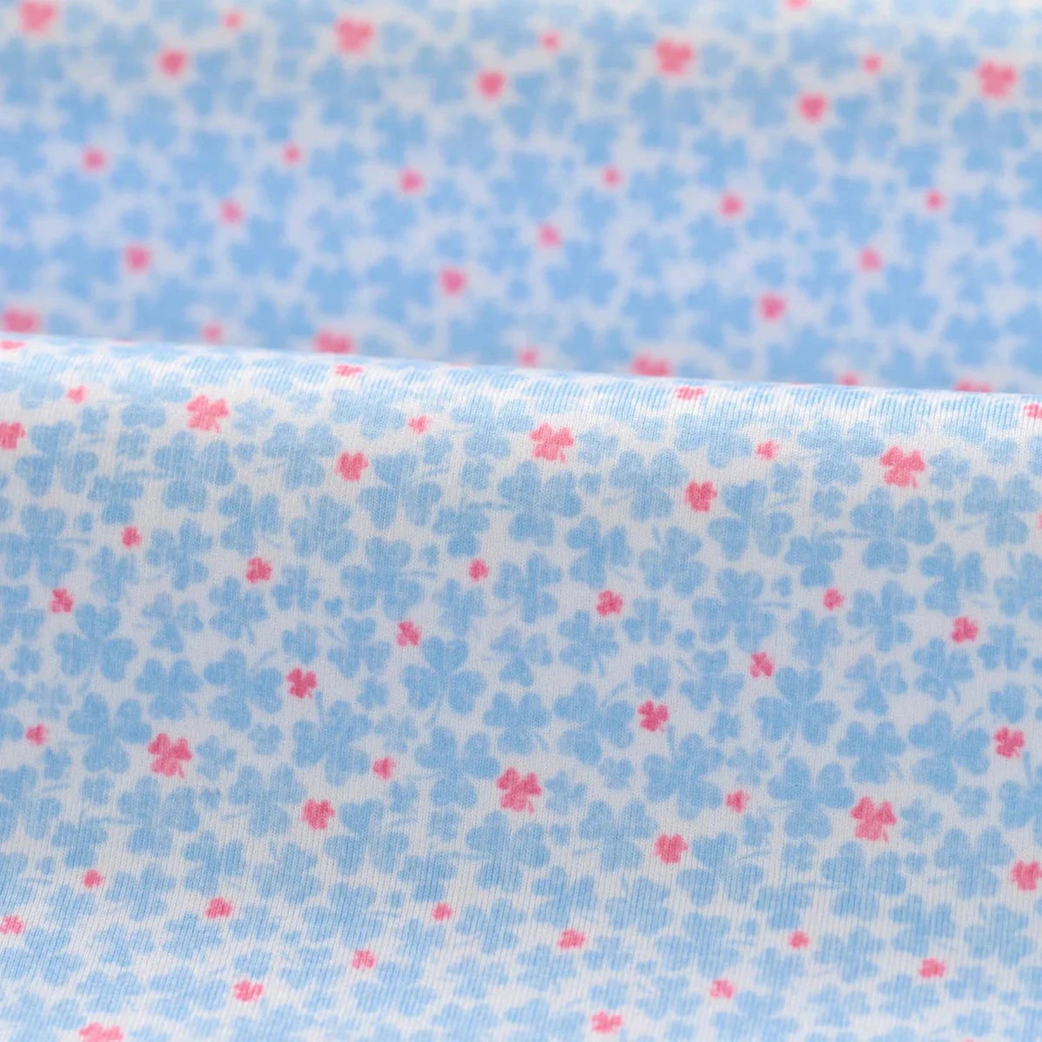 Floral patterned fabric with small blue flowers and pink centers on a light blue background