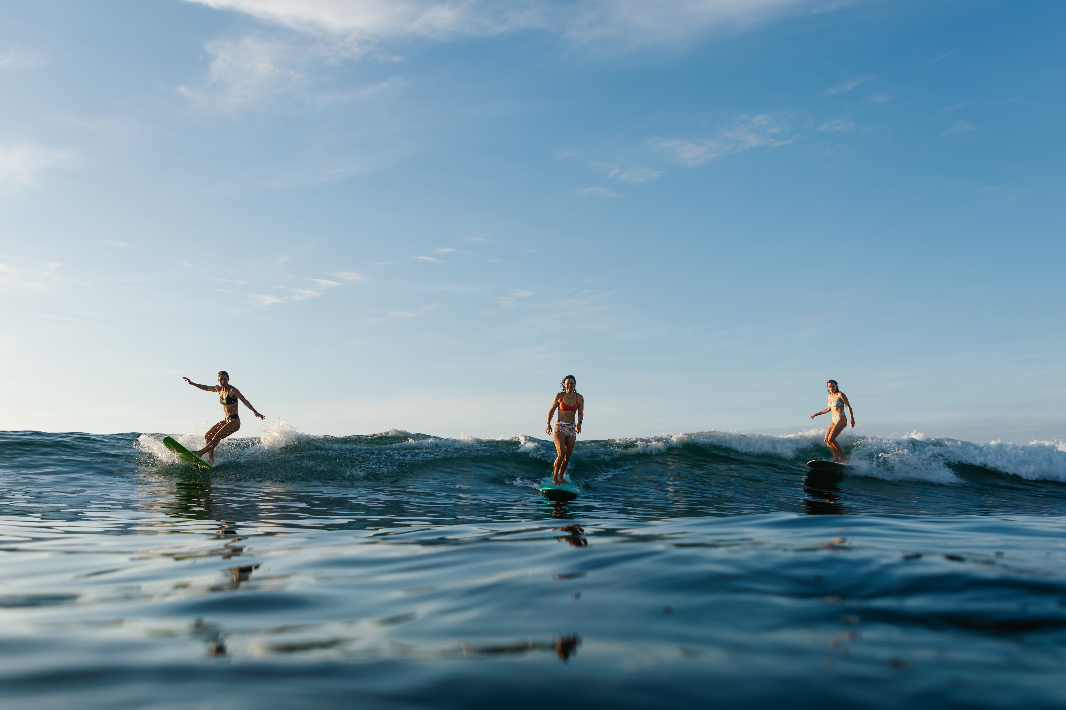 Three people paddleboarding on a calm ocean with a clear blue sky.
