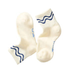 Pair of cream-colored socks with blue wave patterns on a white background