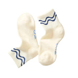 Pair of cream-colored socks with blue wave patterns on a white background
