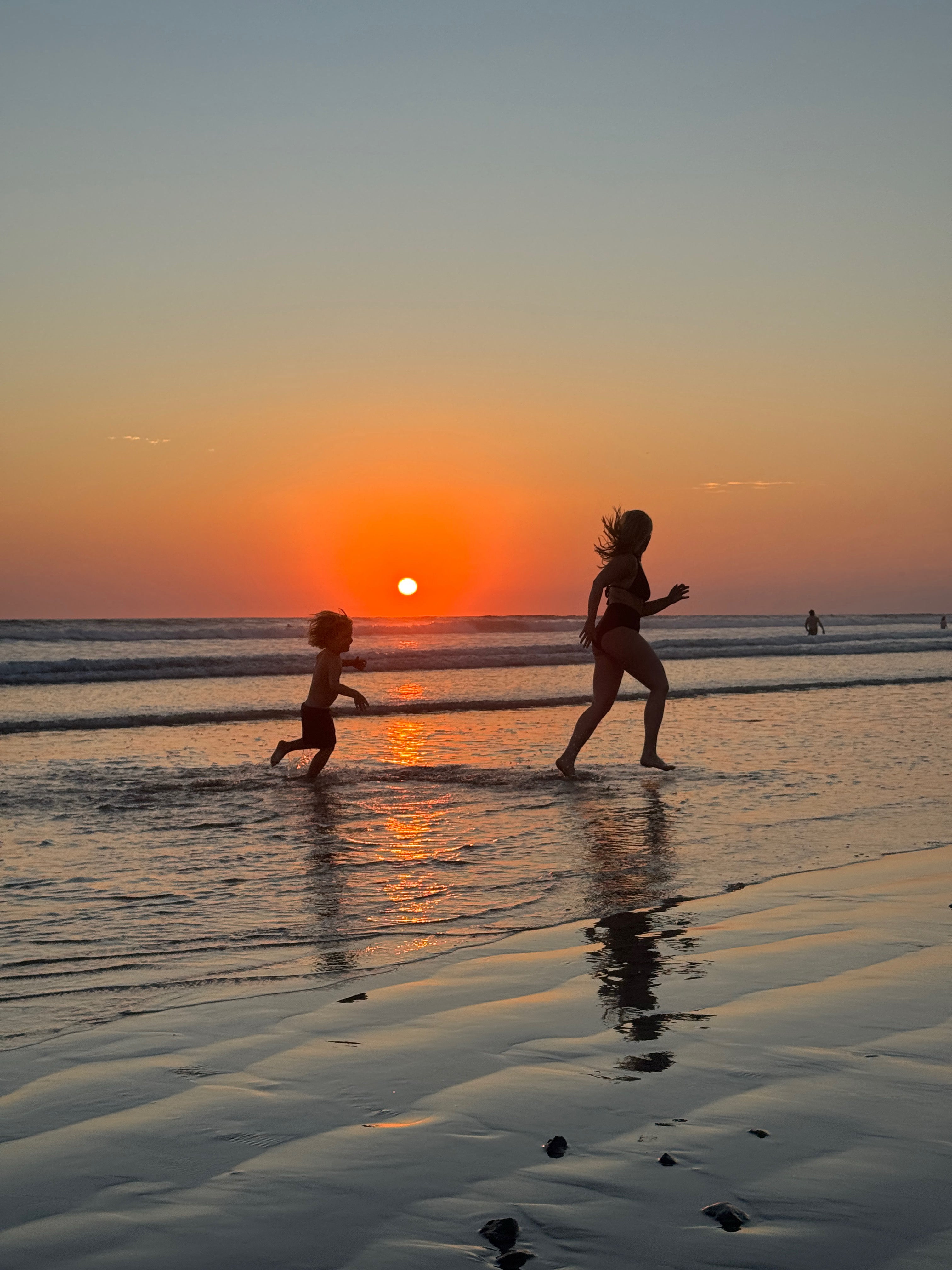 Two people running on a beach at sunset