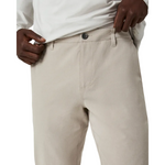 Beige pants worn with a white shirt on a plain background