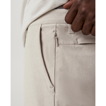 Close-up of beige pants with a hand adjusting the waistband on a white background