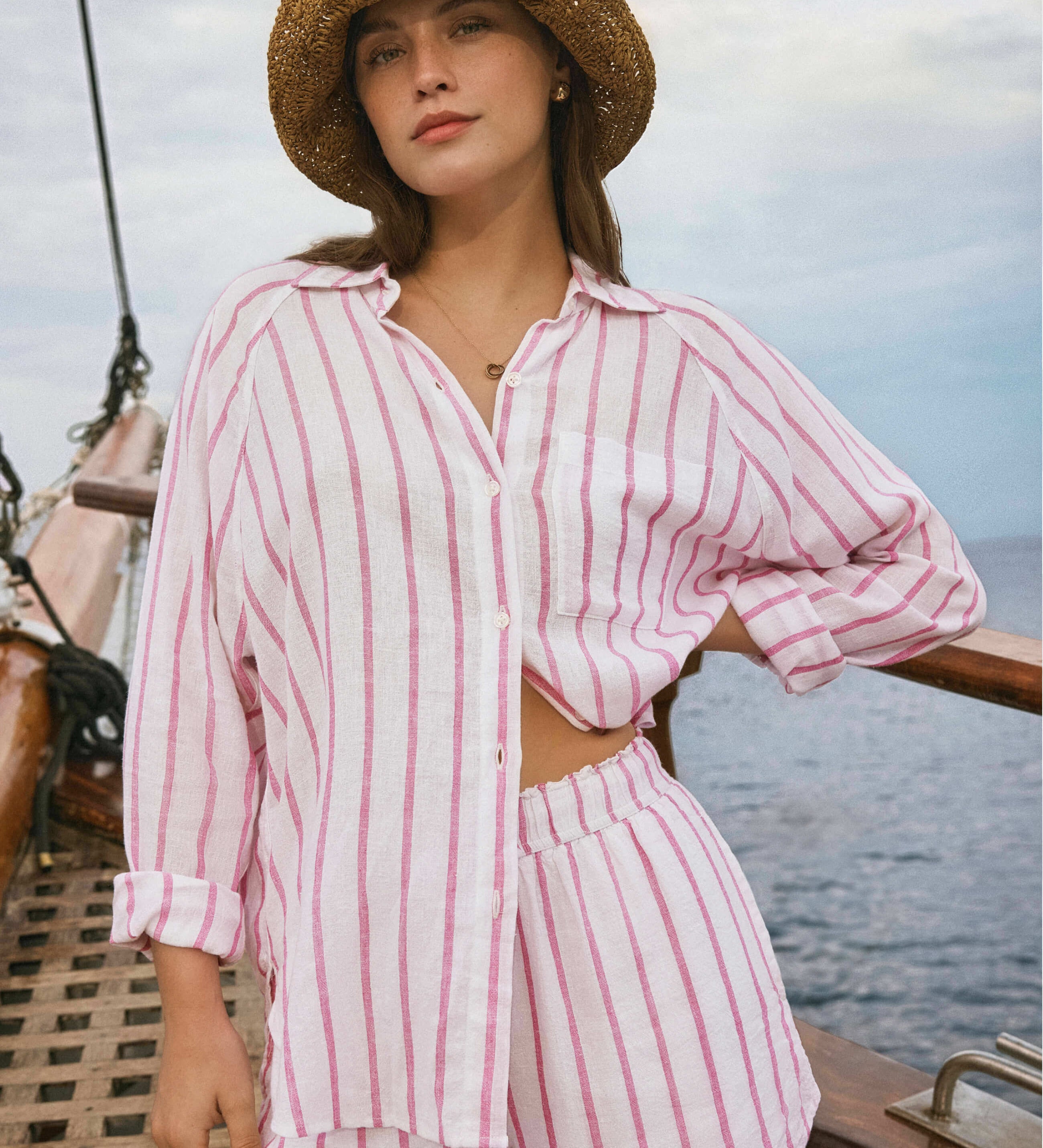 Woman in a pink striped outfit on a boat with water and sky in the background