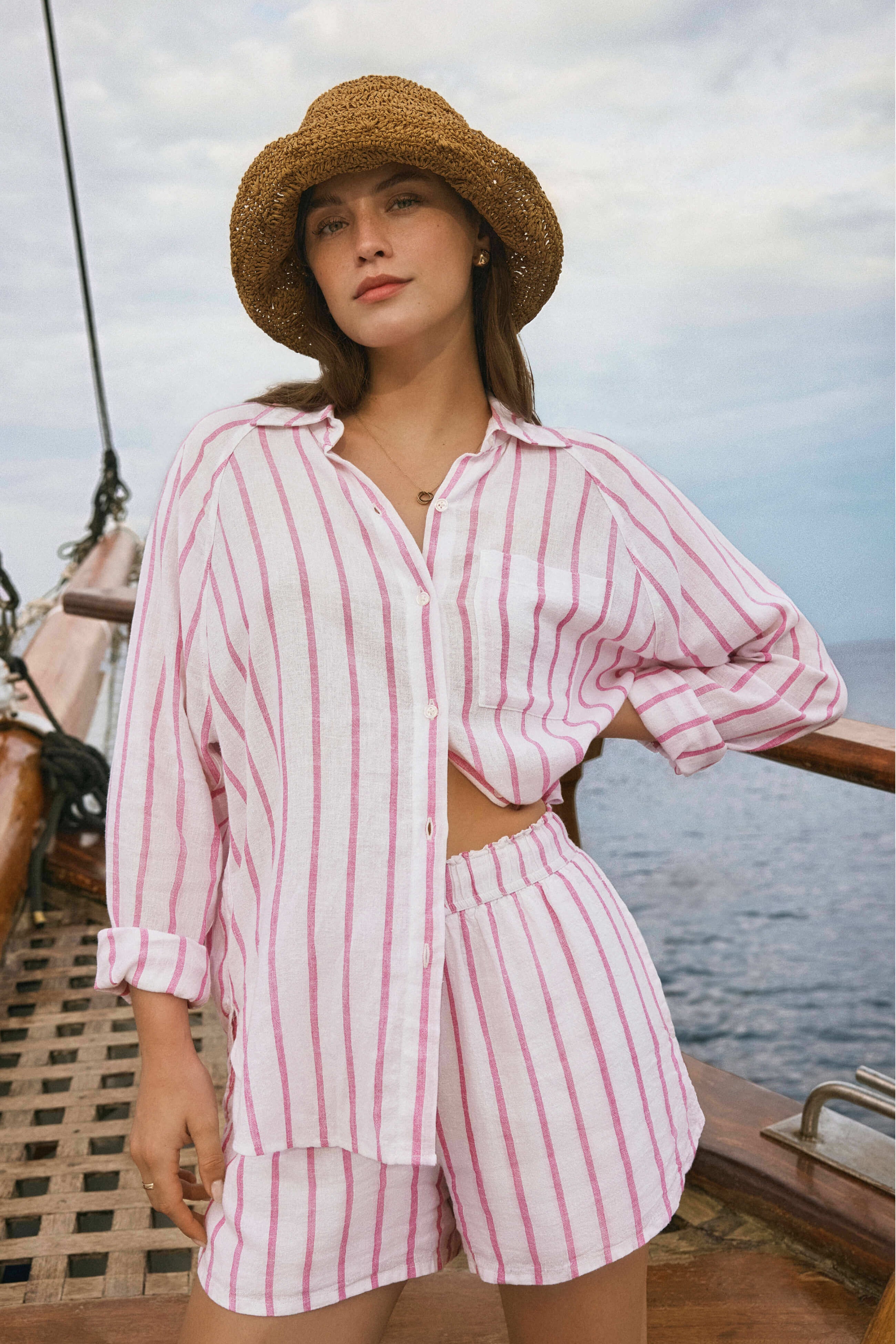 Woman in a pink striped outfit on a boat with water and sky in the background