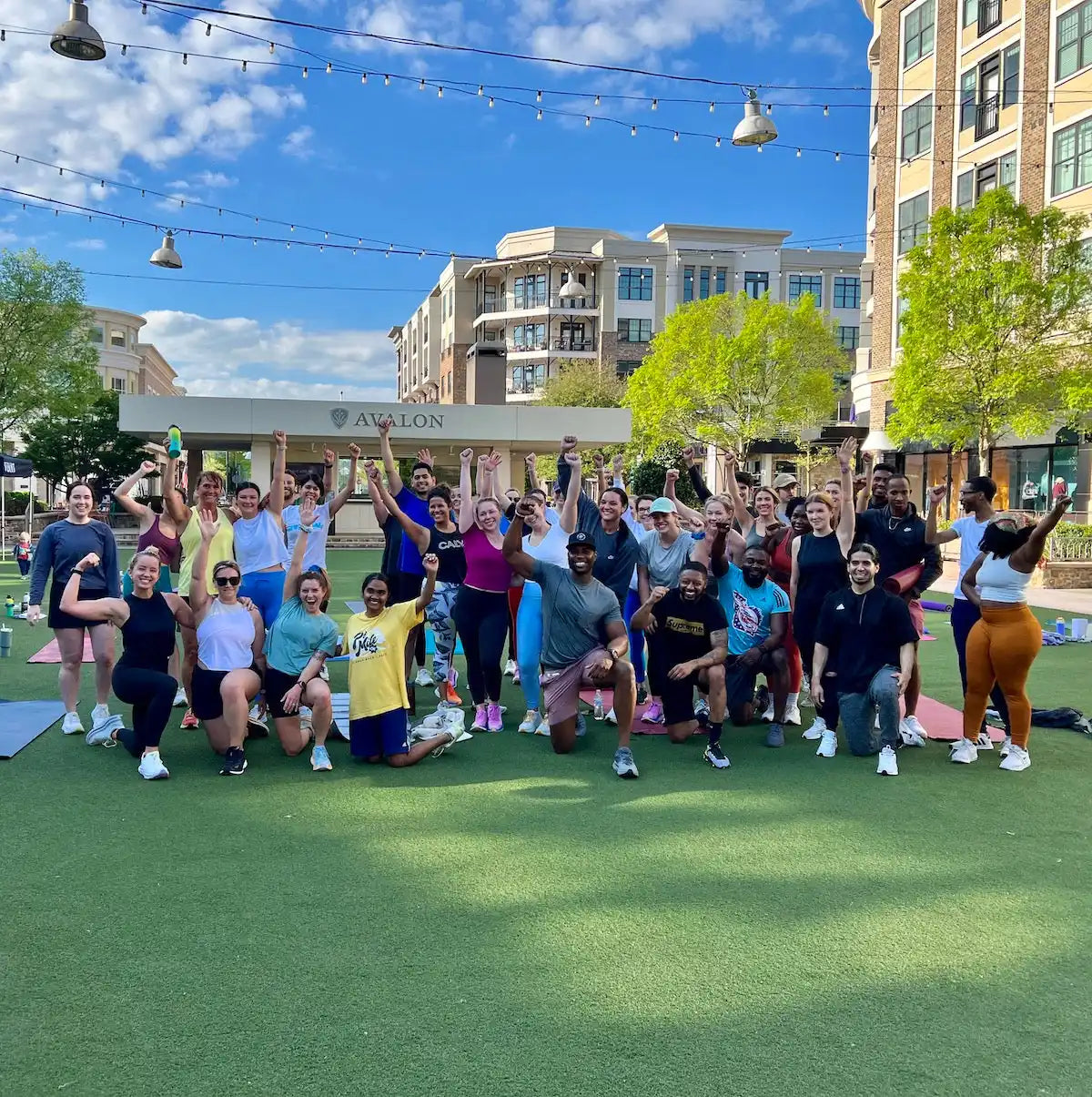 A group of people gathered together on artificial turf in casual athletic wear.