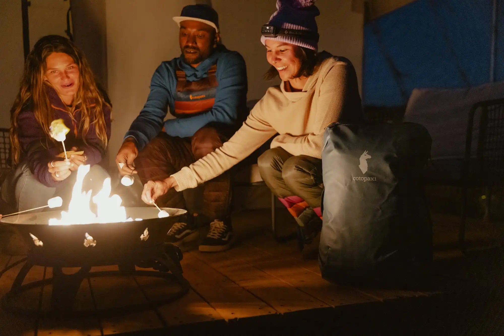 A group of people warming themselves around a glowing fire pit.