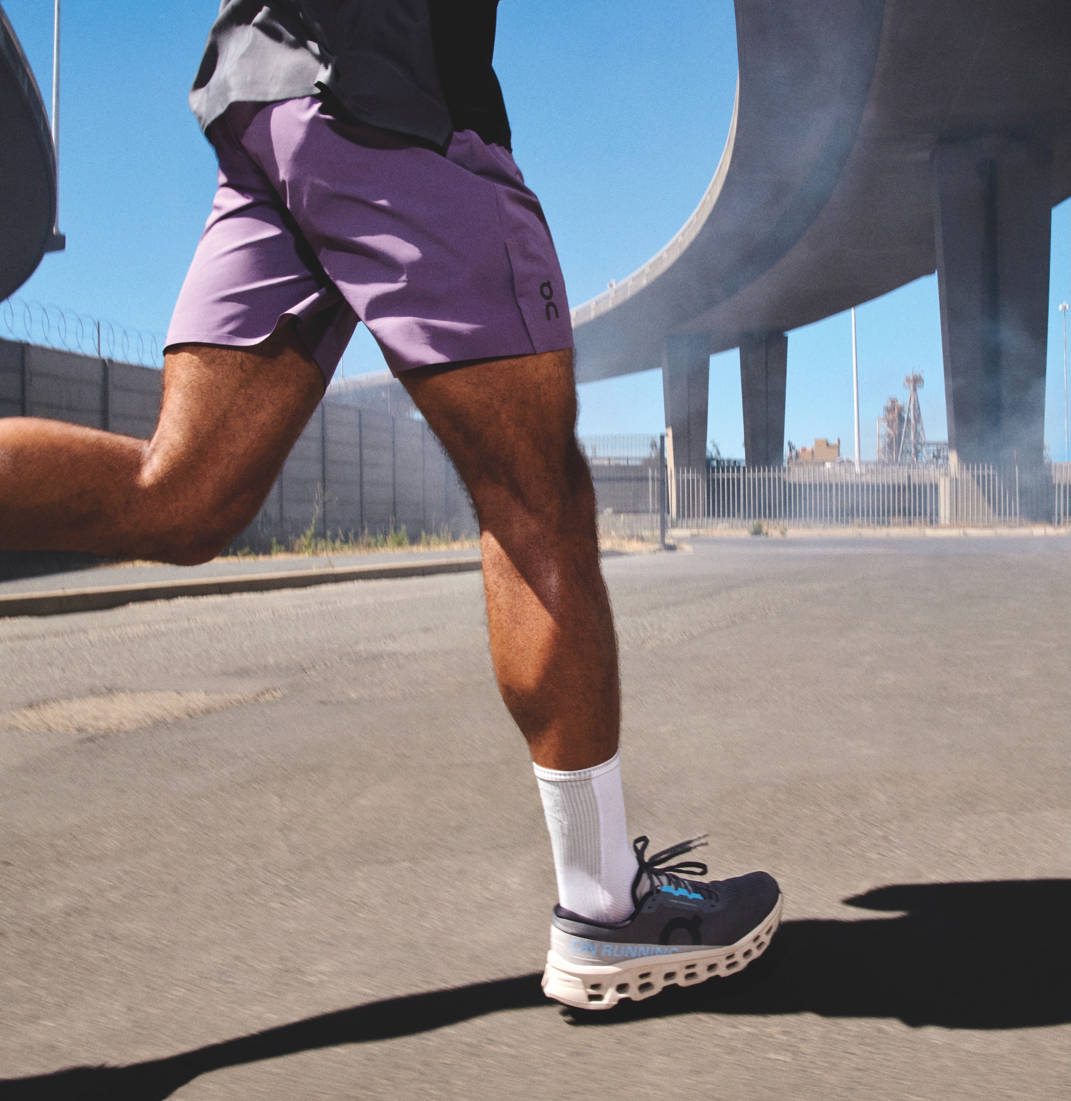 Person running on a road with a clear blue sky and modern architecture in the background