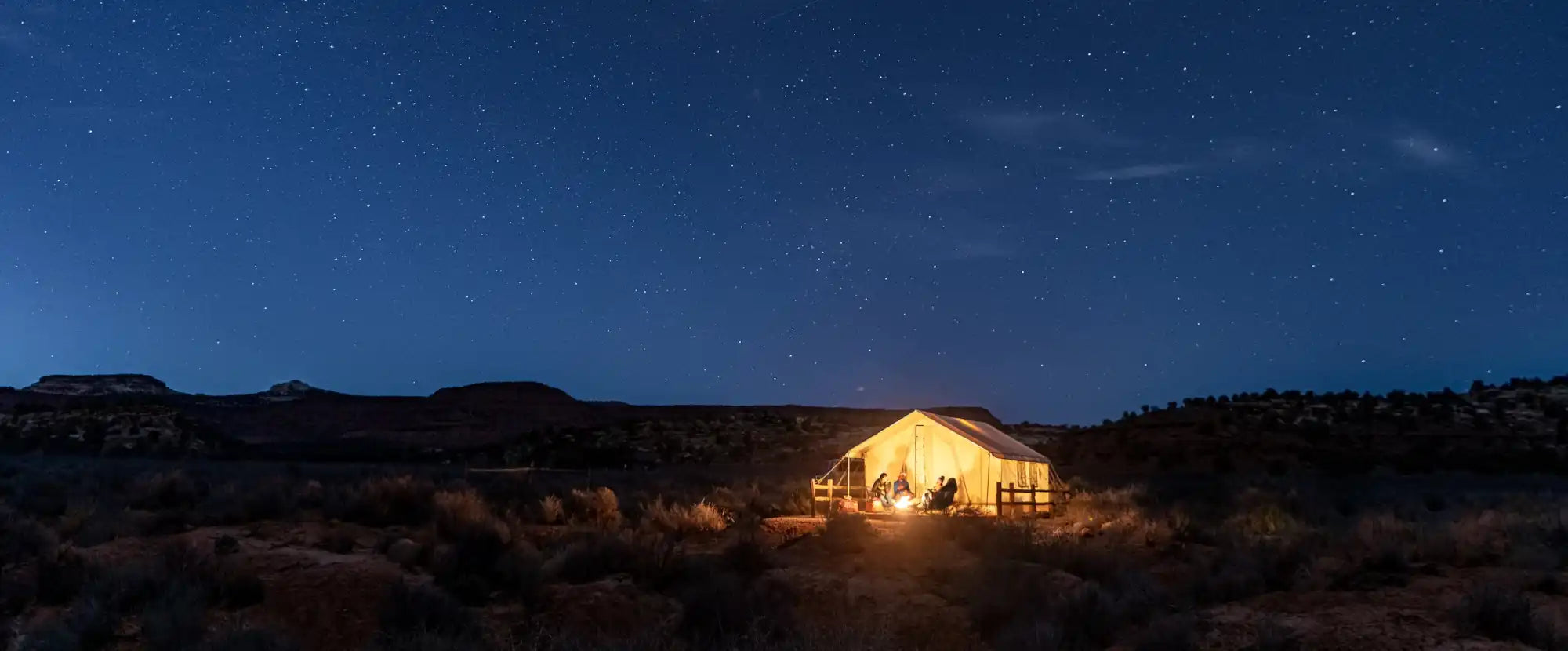 Glowing tent illuminated from within against a dark desert landscape.