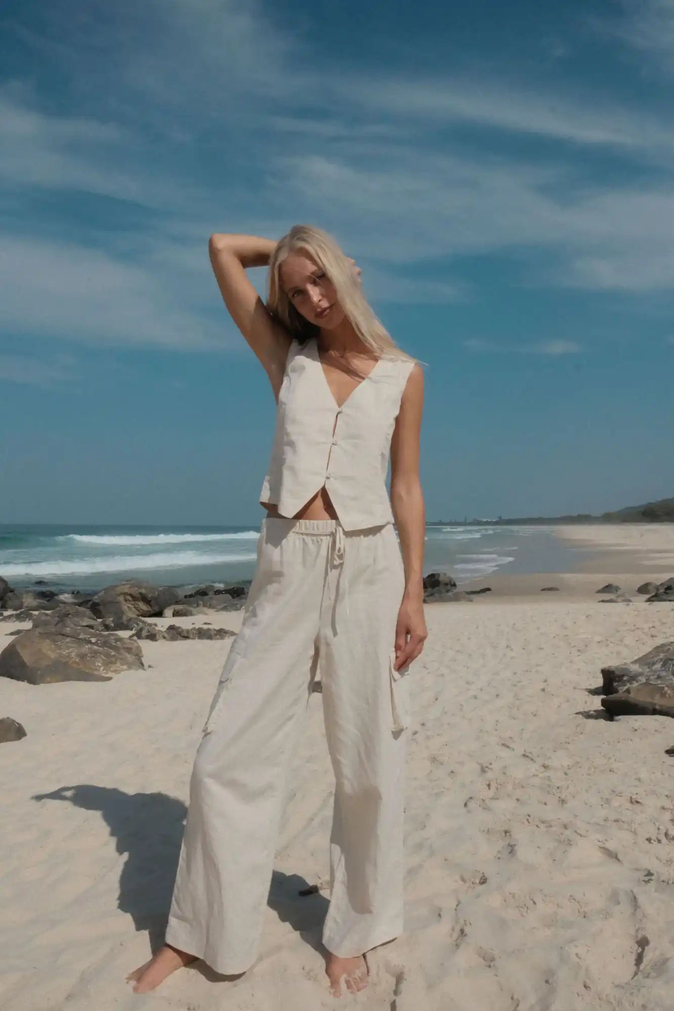 Woman in beige vest and pants.